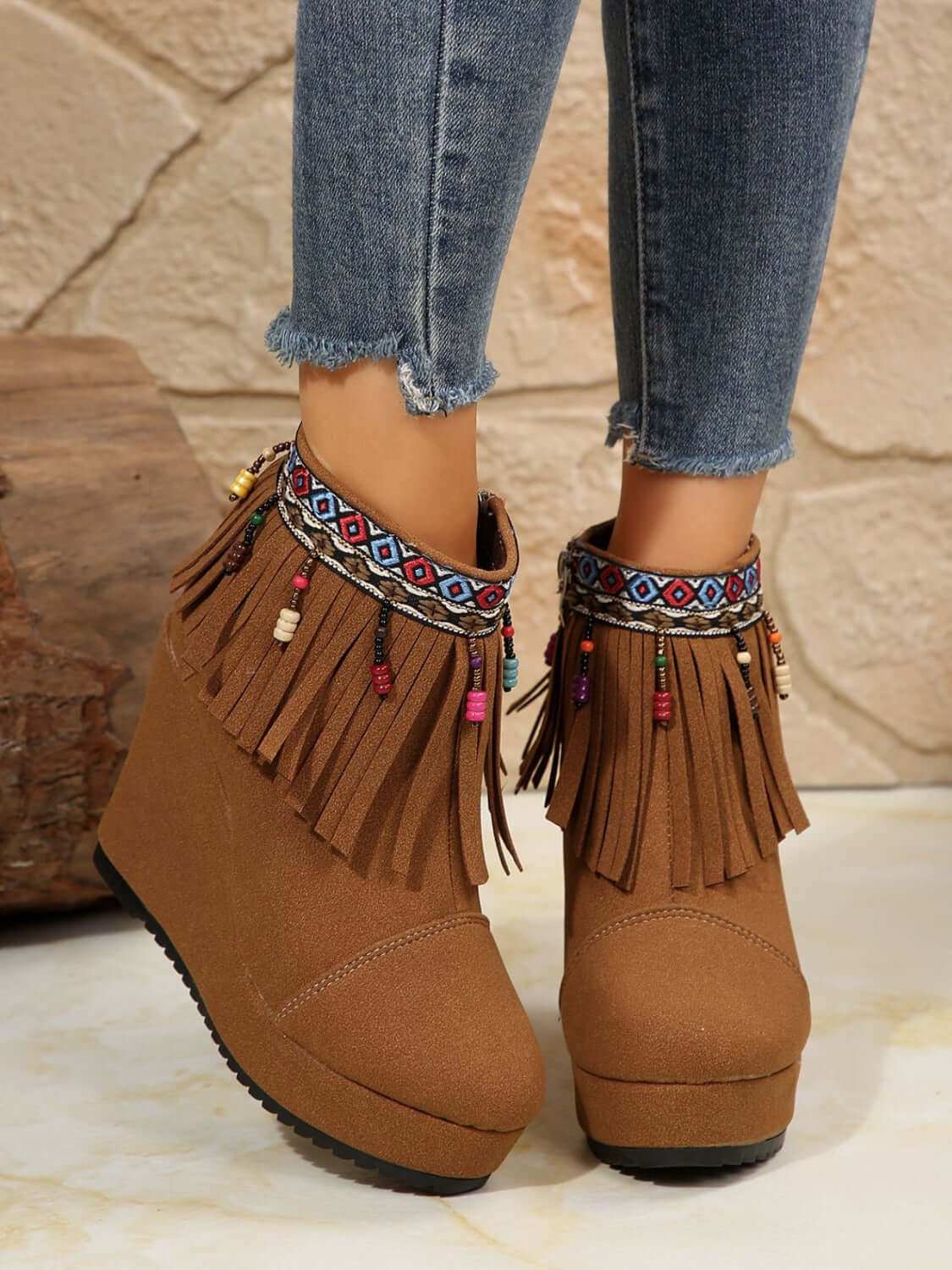 Fringe suede wedge boots with decorative beads and high heel.