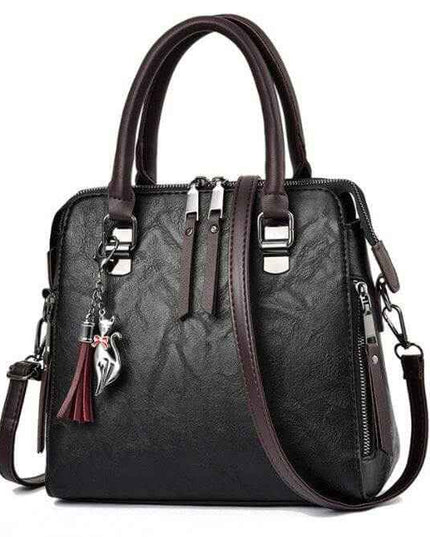 Luxury ladies hand bag with crossbody straps and tassel charm, featuring soft material and zipper closure.