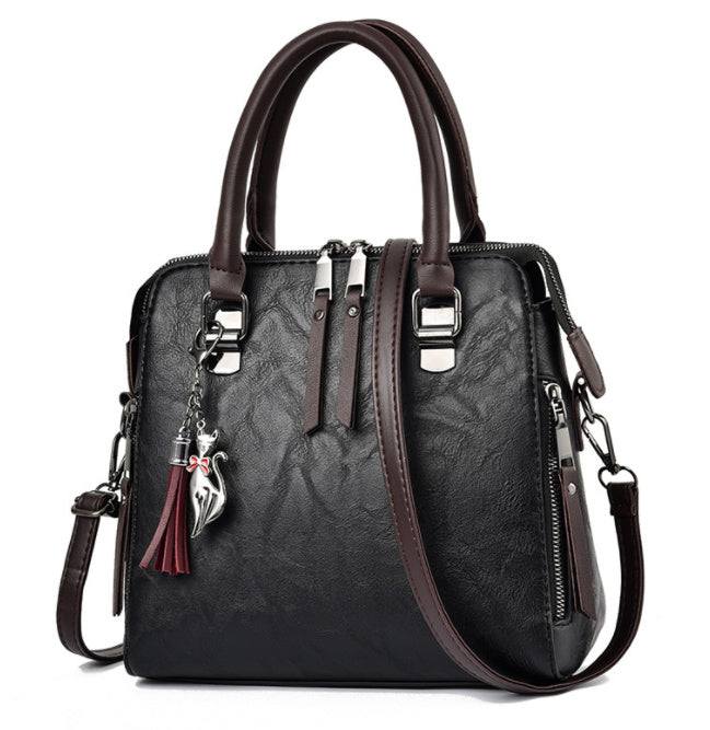 Luxury ladies hand bag with crossbody straps and tassel charm, featuring soft material and zipper closure.