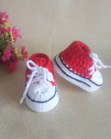 Hand-knitted baby bootees in red and white with floral background.