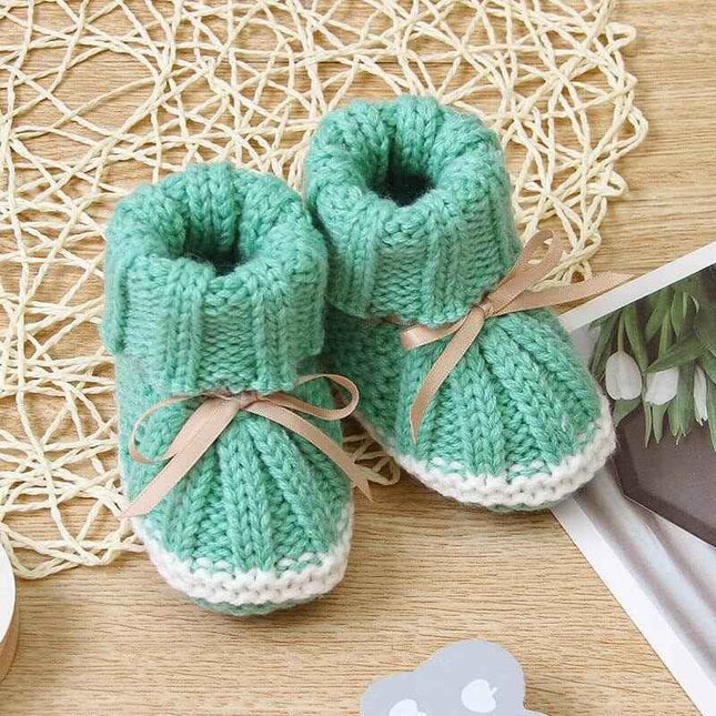 Fashionable and lightweight toddler shoes in green with decorative bows on a woven mat.