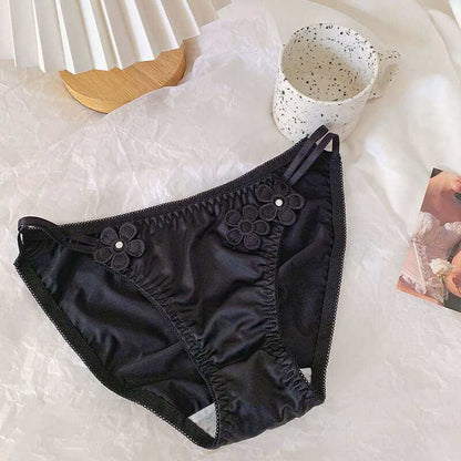 Silky black low waist briefs with embroidered floral decorations.