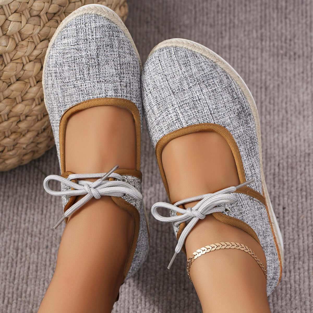 Tied Cutout Wedge Slip-Ons in grey with bow detail and beige trim on a carpeted floor.