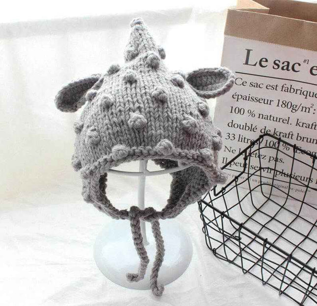 Hand knitted baby hat with cartoon ears and woven balls.