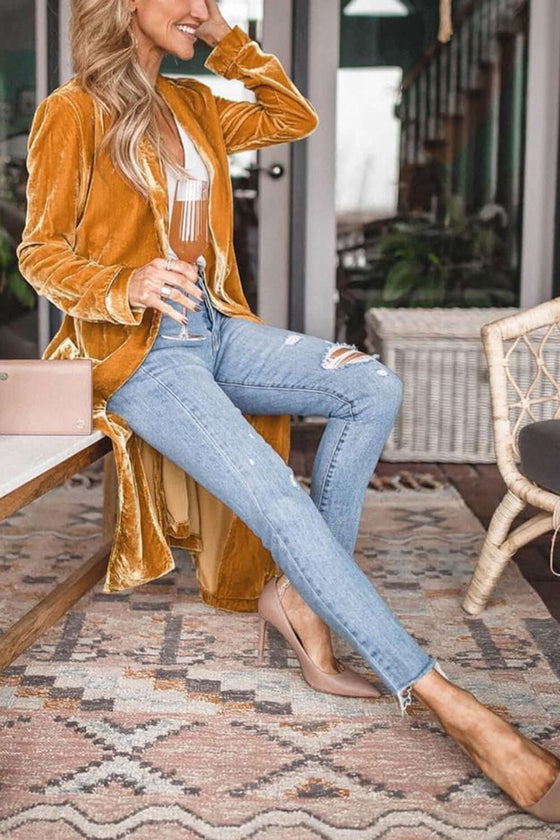 Open Front Long Sleeve Coat in mustard color worn by a woman sitting indoors, paired with jeans and holding a drink.