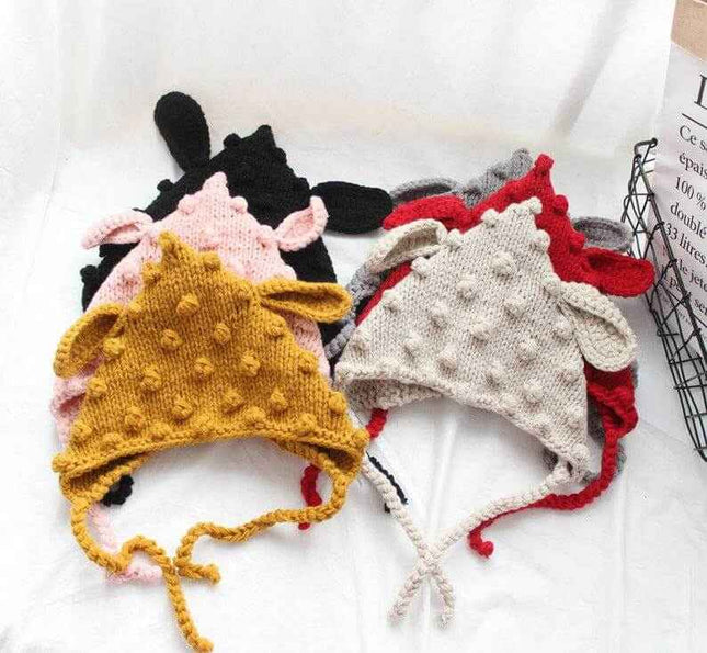 Hand knitted baby hats with cartoon ears and colorful woven balls.