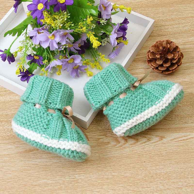 Fashionable and lightweight toddler shoes in green with white trim, suitable for boys and girls, placed on a wooden surface with flowers and pinecone.