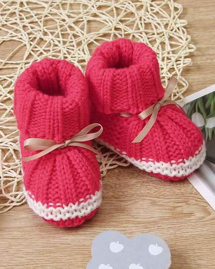 Fashionable and lightweight toddler shoes in red with white trim on a wooden surface.