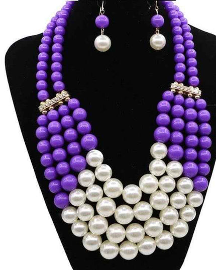 Bohemian jewelry set with purple and white simulated pearls on black display.