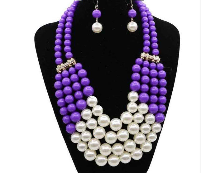 Bohemian jewelry set with purple and white simulated pearls on black display.