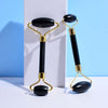 Black jade facial massage rollers on a white surface, enhancing skincare routine.