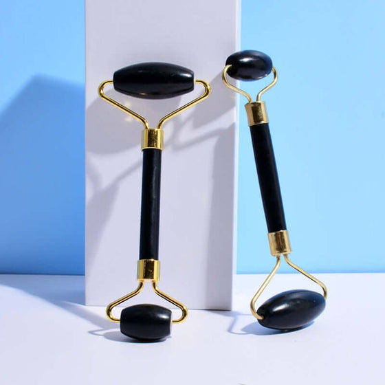 Black jade facial massage rollers on a white surface, enhancing skincare routine.