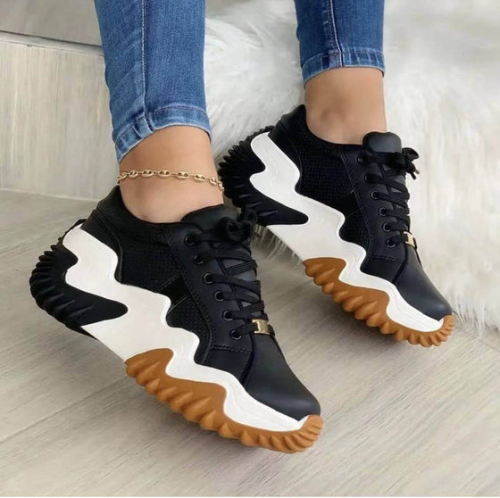 Women's lace-up sports sneakers in black with white and tan soles, featuring a unique design and sponge cake heels.