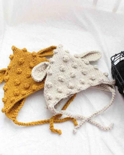 Hand knitted baby hats with cartoon ears and woven balls.