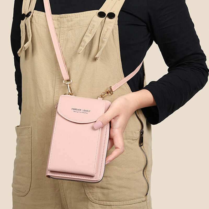 Women mobile phone crossbody large wallet shoulder bag in pink PU leather worn over a beige outfit.